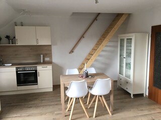 dinner table, kitchen and stairs to large bedroom