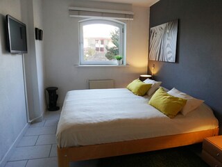 Schlafzimmer mit Doppelbett und Fernseher