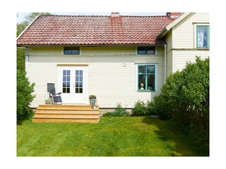 Das Ferienhaus von hinten mit Sitzplatz und Garten