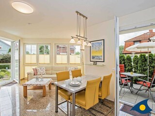 Wohnzimmer mit Essbereich und Zugang zum Balkon (links) und zur Hochterrasse (rechts)