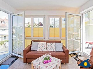 Wohnzimmer mit Zugang zum Balkon (links) und zur Dachterrasse (rechts)
