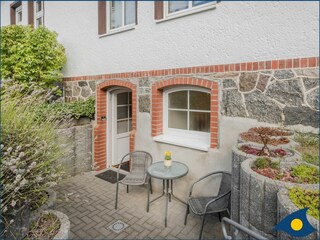Eingang Wohnung mit kleiner Terrasse und Sitzmöbel