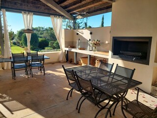 überdachte Terrasse mit Sitzgruppen und Holzkohlegrill