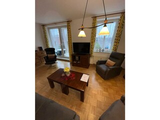 Großes Wohnzimmer mit Parkettboden und Balkonzugang
