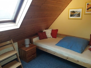 Schlafzimmer mit Einzelbett und Reisebett