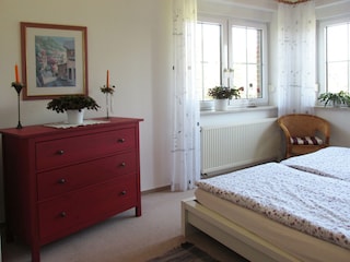 großzügiges Schlafzimmer mit Bett und Kommode