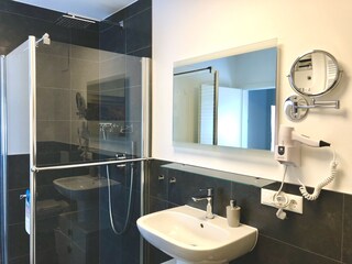 Badezimmer mit bodentiefer Regendusche und Föhn