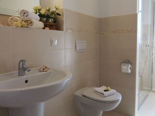 Das helle Badezimmer mit ebenerdiger Dusche.