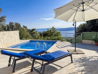 Der Pool mit Sonnenliegen und Meerblick
