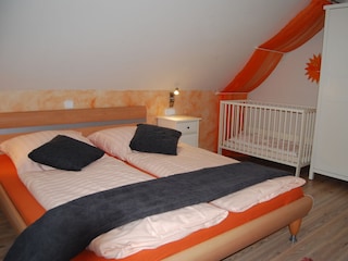 erstes Schlafzimmer mit Doppelbett und Babybett