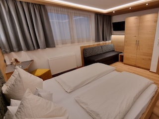 Schlafzimmer mit Doppelbett, Couch und Flat TV