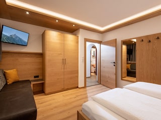 Schlafzimmer mit Doppelbett, Couch und Flat TV