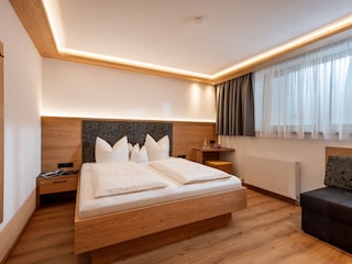 Schlafzimmer mit Doppelbett, Couch und Flat TV
