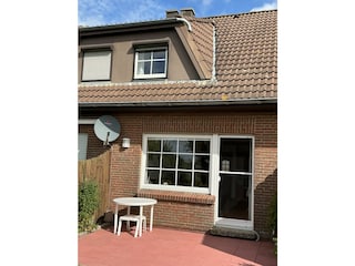 Terrasse steht mit Stühlen und Sonnenschirm zur Verfügu