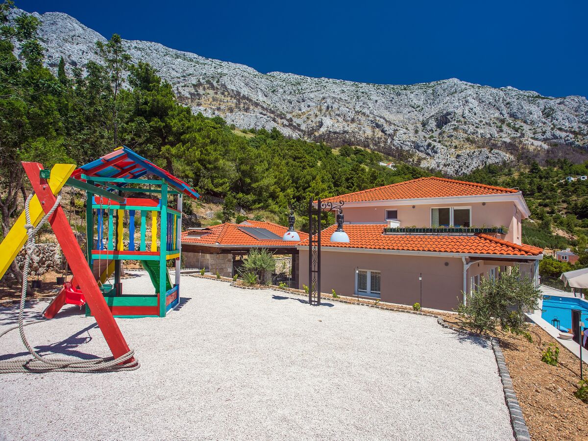 Spielplatz mit Schaukel, Rutsche und Holzhaus