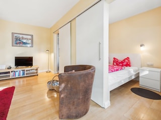 Wohnzimmer mit Blick ins Schlafzimmer 1 mit Doppelbett