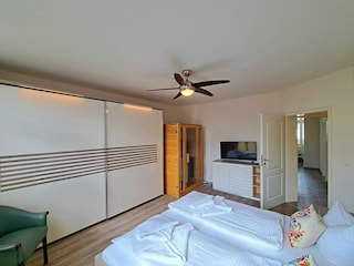 1. Schlafzimmer mit Doppelbett, TV, Kleiderschrank, Infrarotsaunakabine, Zugang zum Balkon