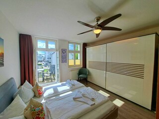 1. Schlafzimmer mit Doppelbett, TV, Kleiderschrank, Infrarotsaunakabine, Zugang zum Balkon