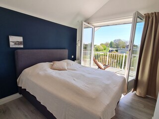 Gemütliches Schlafzimmer mit Boxspringbett und Balkon