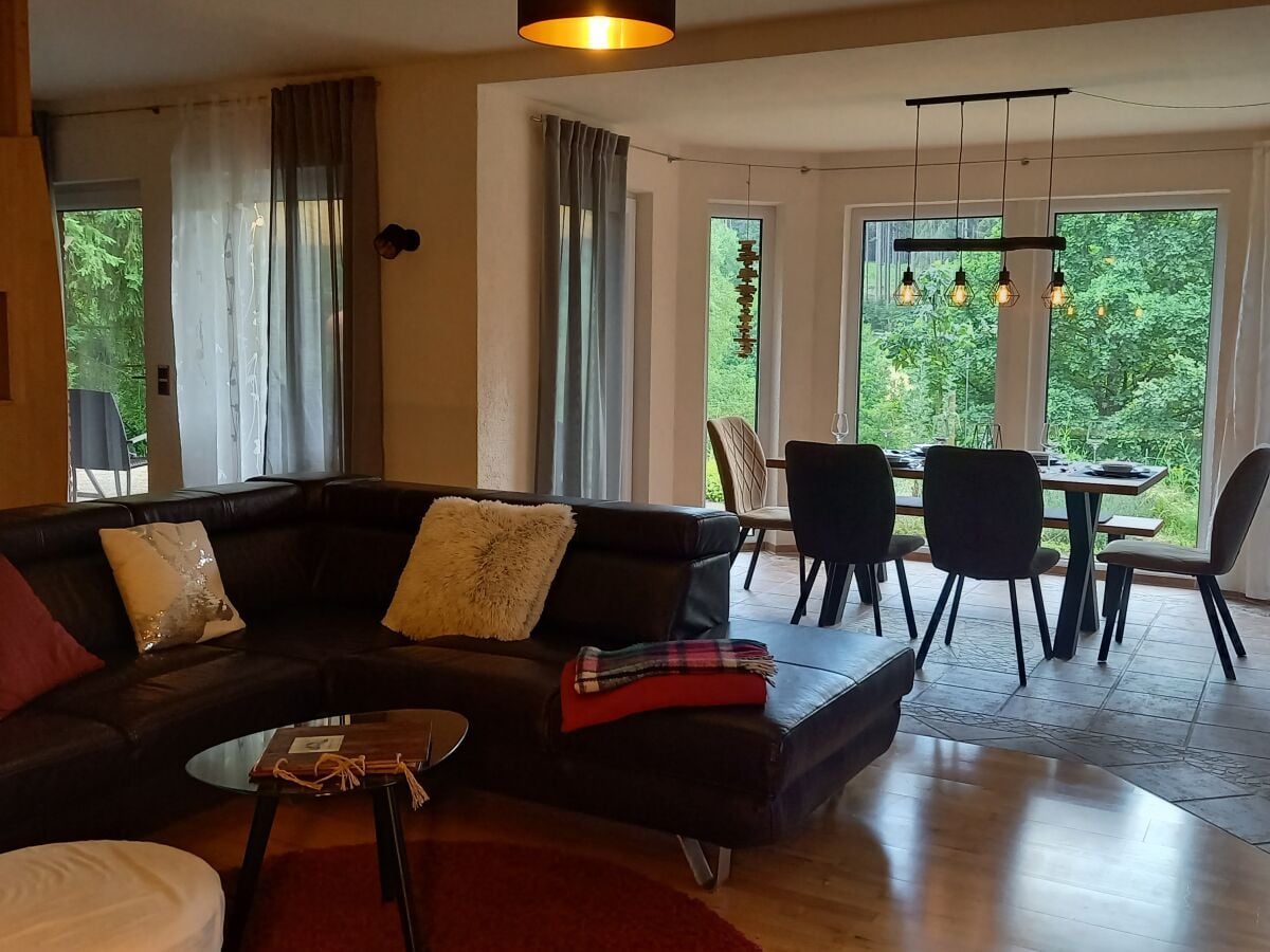 das Wohnzimmer mit Couch und Esstisch