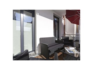 Der Balkon mit Gartenmöbeln und Sonnenschirm