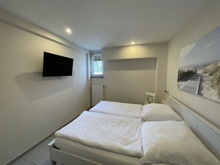 Schlafzimmer mit Doppelbett und TV