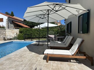 Blick auf die großzügige Poolterrasse mit Liegestühle u