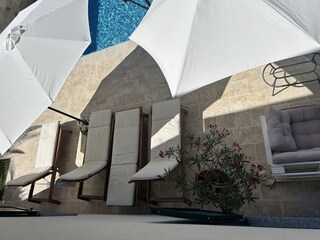 Blick auf die großzügige Poolterrasse mit Liegestühle u