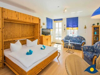 Wohnbereich mit Schrankdoppelbett und Zugang zur Terrasse