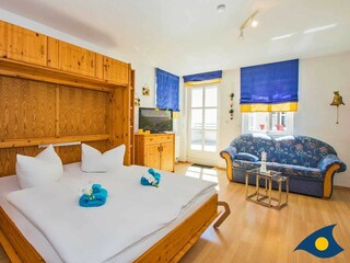 Wohnbereich mit Schrankdoppelbett und Zugang zur Terrasse