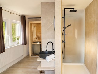 Großzügiges Bad mit Spiegel, Dusche und Saunabereich