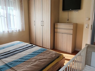 Schlafzimmer mit Doppelbett und Babybett