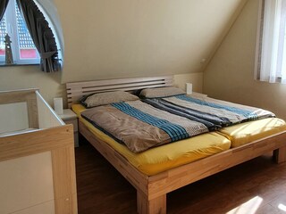 Schlafzimmer mit Doppelbett und Babybett