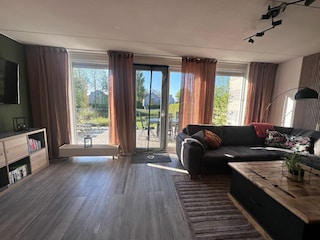 Wohnzimmer mit großen Fenstern und Zugang in den Garten