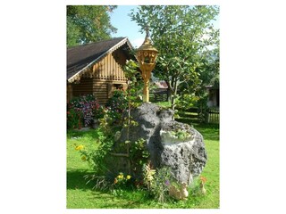 Miniglockenturm mit Gartenhaus im Hintergrund