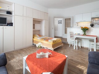 Wohn-, Küchenbereich mit ausgeklapptem Schrankbett