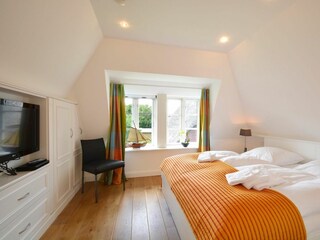 Das erste Schlafzimmer im Obergeschoss ist mit einem luxuriösen Doppelbett ausgestattet.