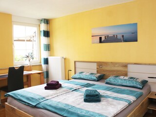 Schlafzimmer mit Doppelbett und Schreibtisch