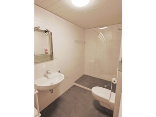 Badezimmer mit Bodendusche und Toilette, Waschmaschine