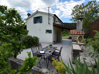 Offene Terrasse hinter dem Haus mit gemauertem Grill