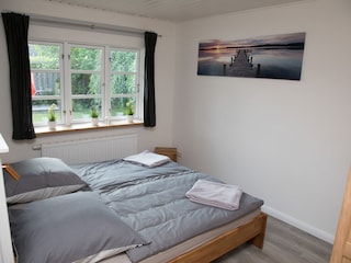 Schlafzimmer mit Doppelbett und Blick in den Garten