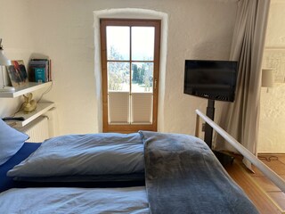 Blick vom Bett aus in den Garten und auf die Berge