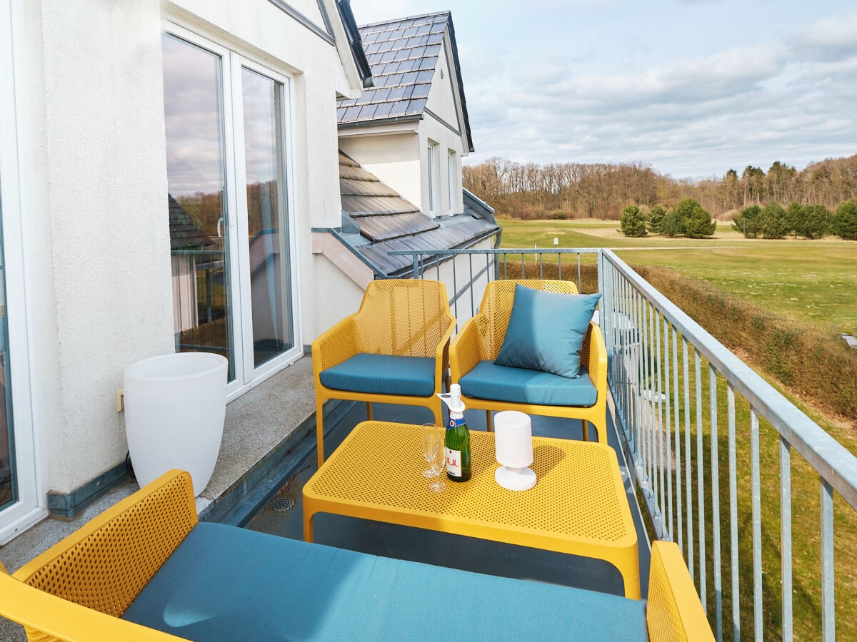 Sonniger Balkon mit Golfplatzgrill und Loungegruppe