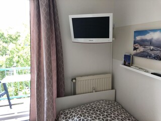 Schlafzimmer zwei Einzelbetten mit Fernseher und Balkonzugang