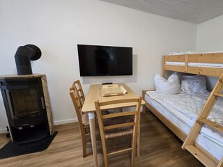 Wohnzimmer mit Kaminofen und Etagenbett