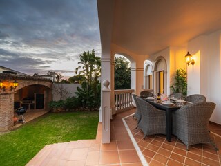 Dining table and seating area on terrace with pool view