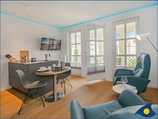 Wohnbereich mit offener moderner Küche und Zugang zum Balkon