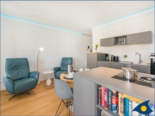 Wohnbereich mit offener moderner Küche und Zugang zum Balkon