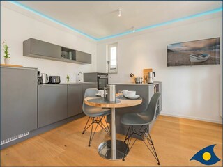 Wohnbereich mit offener moderner Küche und Zugang zum Balkon