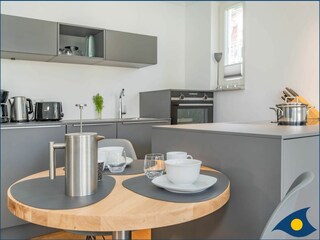 Wohnbereich mit offener moderner Küche und Zugang zum Balkon